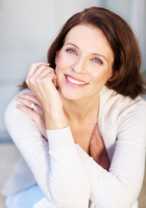 A woman smiling with her hands on her chin.